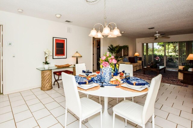 dining room with a textured ceiling, light tile patterned floors, and ceiling fan with notable chandelier