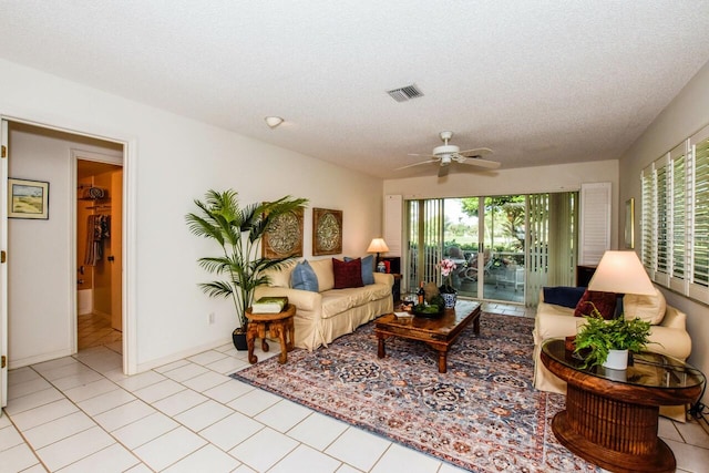 tiled living area featuring visible vents, ceiling fan, a textured ceiling, and baseboards