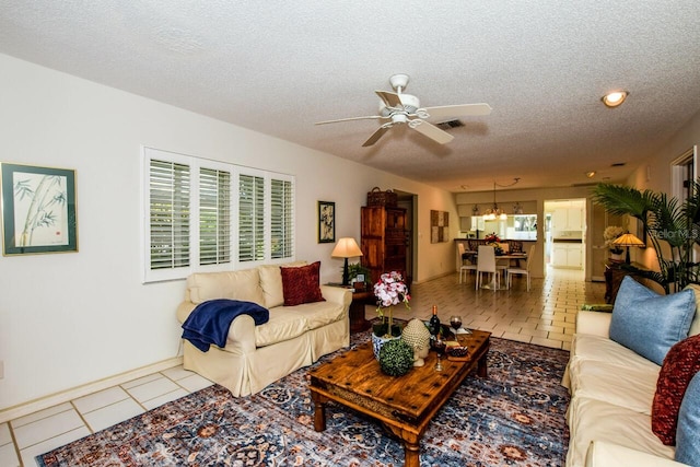 living area featuring a ceiling fan, visible vents, a textured ceiling, and tile patterned floors