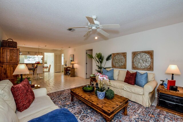 living room featuring light tile patterned flooring, a textured ceiling, and ceiling fan