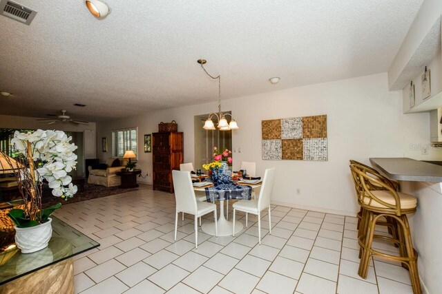 dining room featuring a textured ceiling, light tile patterned flooring, and ceiling fan with notable chandelier