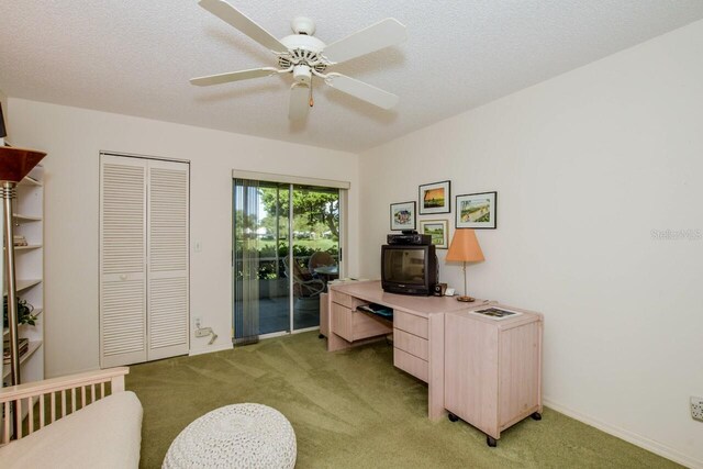 carpeted home office featuring a textured ceiling and ceiling fan