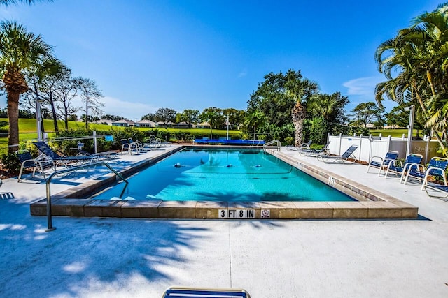 community pool with a patio area and fence