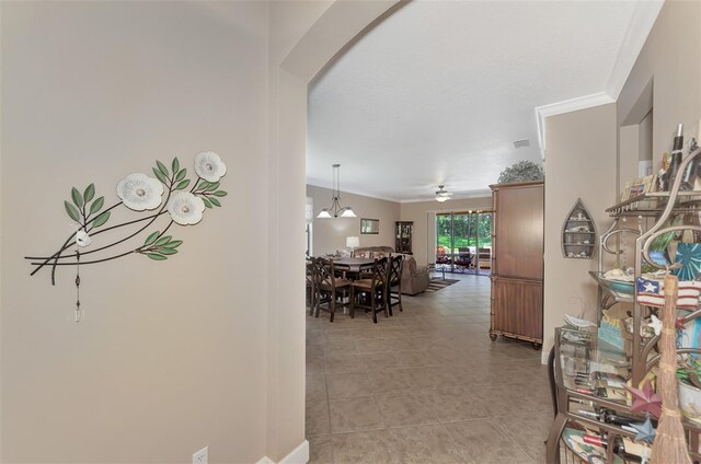 hallway with light tile patterned floors, crown molding, and a chandelier