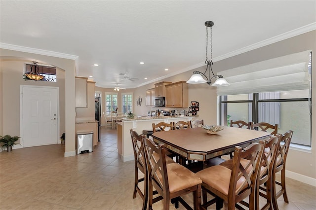 tiled dining room with ceiling fan and crown molding