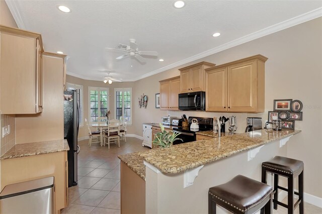 kitchen with black appliances, light brown cabinetry, a peninsula, and light stone counters