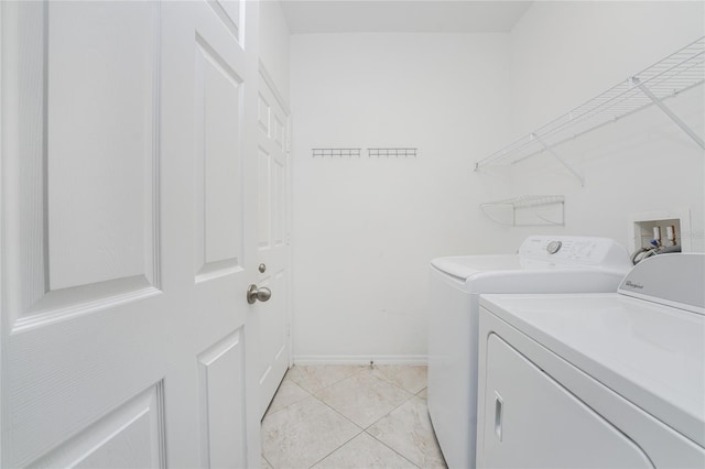 clothes washing area with light tile patterned flooring and washer and clothes dryer