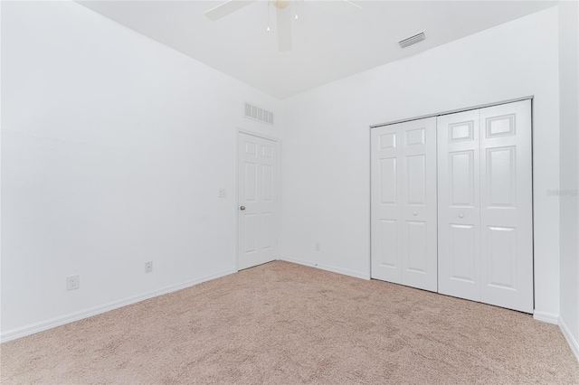 unfurnished bedroom featuring ceiling fan, a closet, and light colored carpet