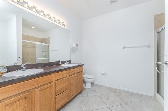 bathroom featuring toilet, vanity, and a shower with shower door