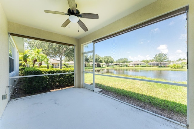 unfurnished sunroom with ceiling fan and a water view