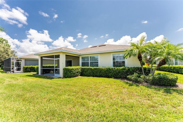 rear view of property with a lawn and a sunroom