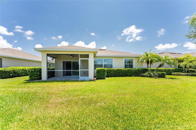 rear view of property featuring a yard and ceiling fan