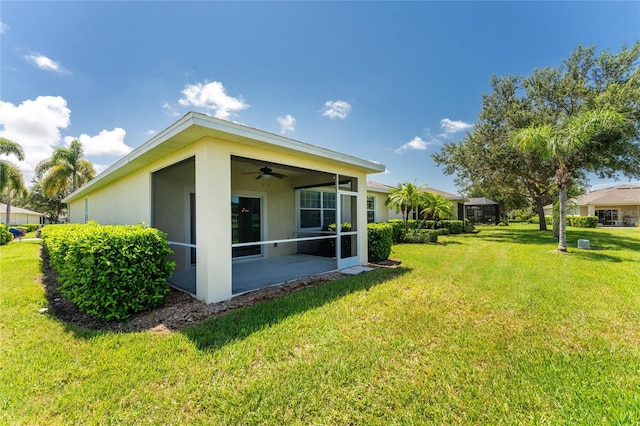 rear view of property featuring a sunroom, a lawn, and ceiling fan