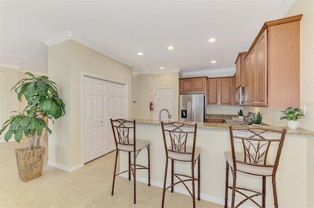 kitchen with a breakfast bar area, light stone counters, kitchen peninsula, stainless steel appliances, and crown molding