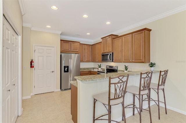 kitchen with appliances with stainless steel finishes, a kitchen bar, light stone counters, kitchen peninsula, and crown molding