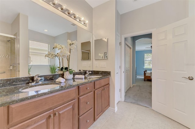 bathroom with a shower with door, vanity, tile patterned floors, and ceiling fan