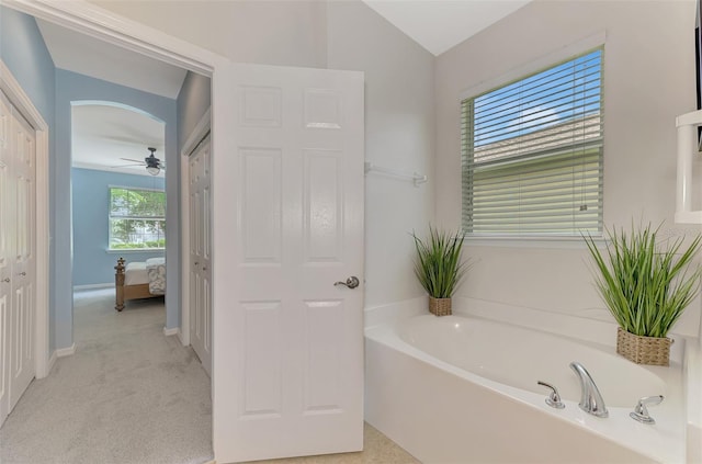 bathroom with a washtub, vaulted ceiling, and ceiling fan