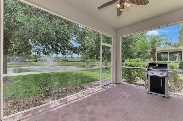 unfurnished sunroom featuring a water view and ceiling fan