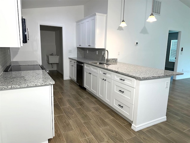 kitchen featuring vaulted ceiling, pendant lighting, backsplash, white cabinetry, and sink