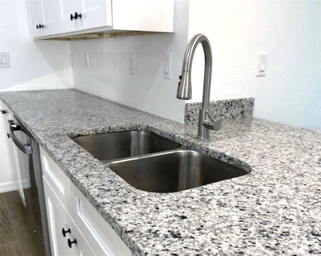 kitchen featuring sink, light stone countertops, and white cabinetry