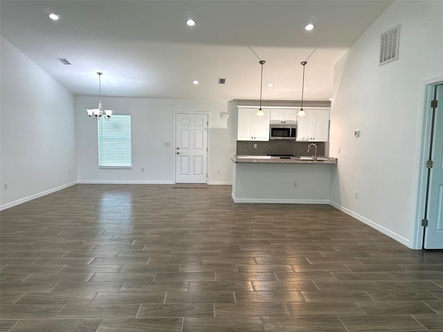 unfurnished living room featuring sink and a chandelier