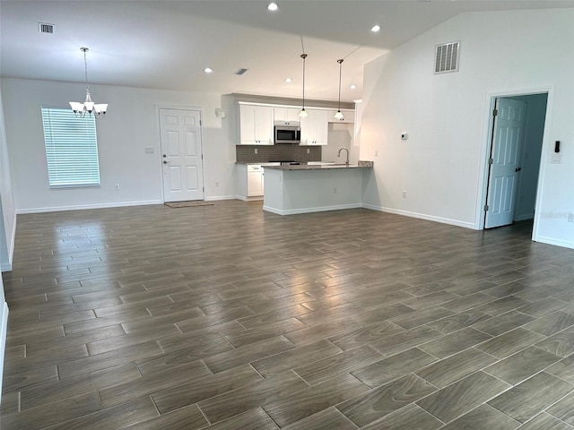 unfurnished living room featuring a notable chandelier, lofted ceiling, and sink