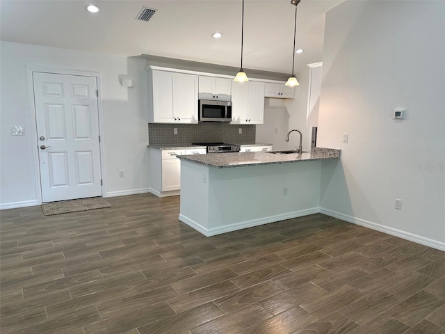 kitchen featuring stainless steel appliances, white cabinetry, kitchen peninsula, and hanging light fixtures