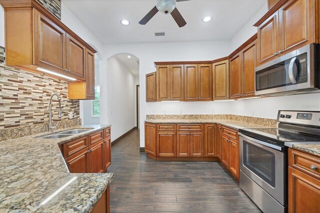 kitchen featuring dark wood-type flooring, backsplash, ceiling fan, appliances with stainless steel finishes, and sink