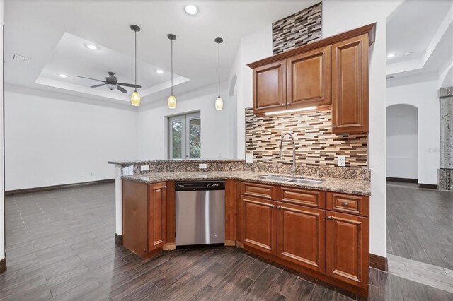 kitchen with sink, stainless steel dishwasher, dark wood-type flooring, ceiling fan, and a raised ceiling