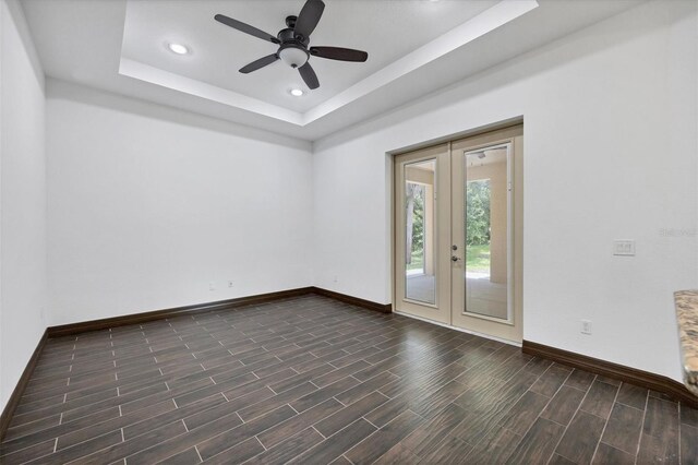 spare room with dark hardwood / wood-style floors, ceiling fan, french doors, and a tray ceiling