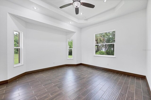 empty room featuring ceiling fan, hardwood / wood-style flooring, and a tray ceiling