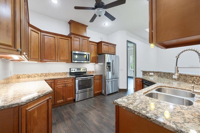 kitchen with stainless steel appliances, sink, ceiling fan, stone countertops, and dark hardwood / wood-style flooring