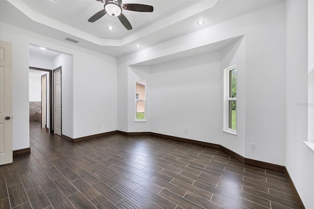 spare room with ceiling fan, dark hardwood / wood-style floors, and a tray ceiling