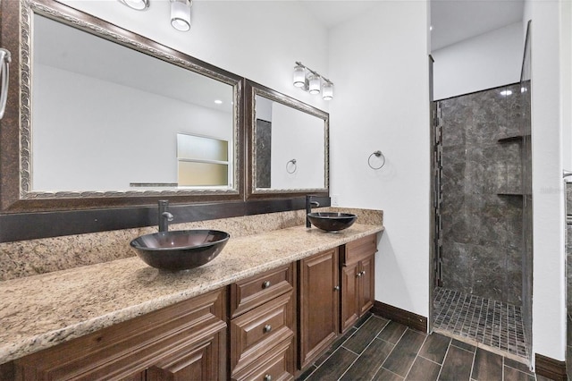 bathroom with a tile shower and dual bowl vanity