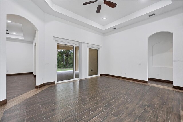 unfurnished room with dark hardwood / wood-style floors, a raised ceiling, and ceiling fan