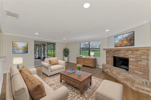 living room with a brick fireplace, light hardwood / wood-style flooring, and crown molding