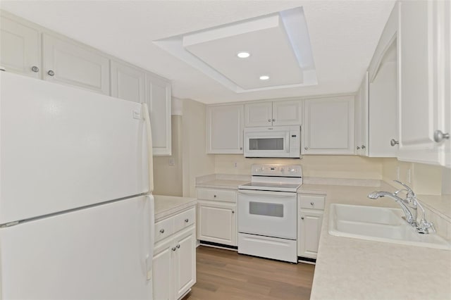 kitchen featuring white cabinetry, white appliances, a raised ceiling, and sink