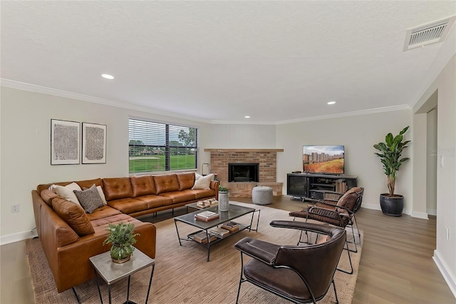 living room with ornamental molding, a fireplace, and light hardwood / wood-style floors