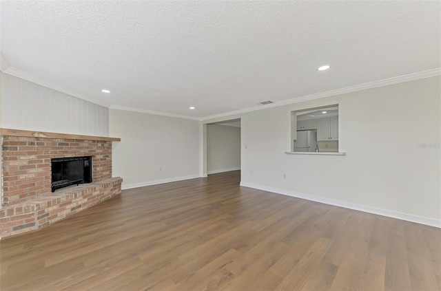 unfurnished living room featuring wood-type flooring, ornamental molding, and a textured ceiling