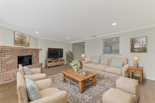 living room with a fireplace, ornamental molding, and light hardwood / wood-style floors