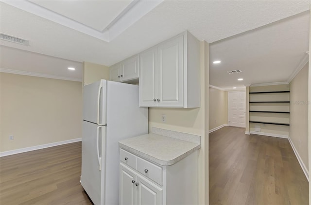 kitchen featuring built in features, white cabinetry, ornamental molding, white fridge, and light wood-type flooring