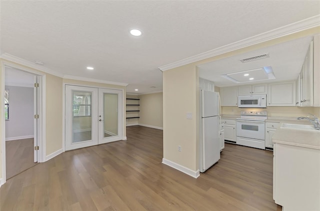 kitchen with white appliances, ornamental molding, sink, and white cabinets