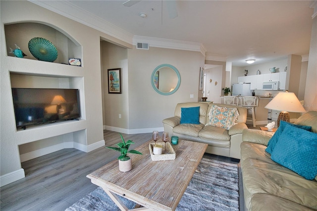 living room with built in features, ornamental molding, and hardwood / wood-style floors