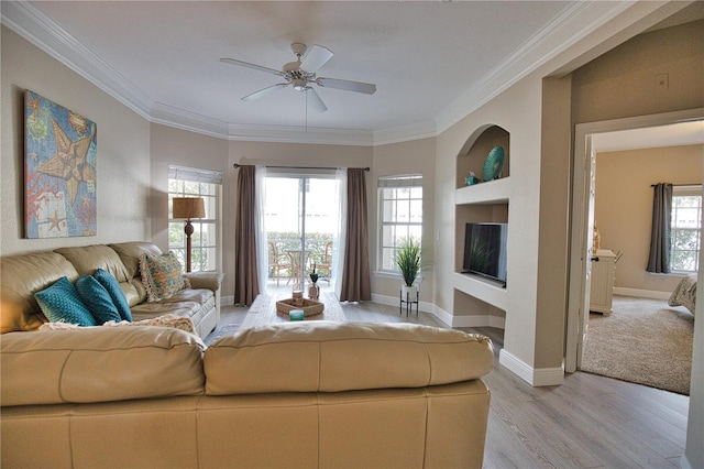 living room with ornamental molding, light wood-type flooring, ceiling fan, and a healthy amount of sunlight