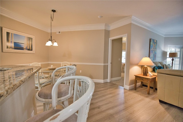 dining space featuring light hardwood / wood-style flooring, an inviting chandelier, and crown molding