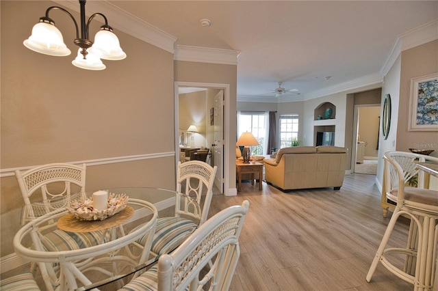 dining area with light hardwood / wood-style flooring, ceiling fan with notable chandelier, and crown molding