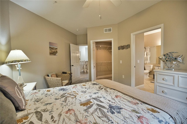 tiled bedroom featuring a closet, connected bathroom, ceiling fan, and a walk in closet