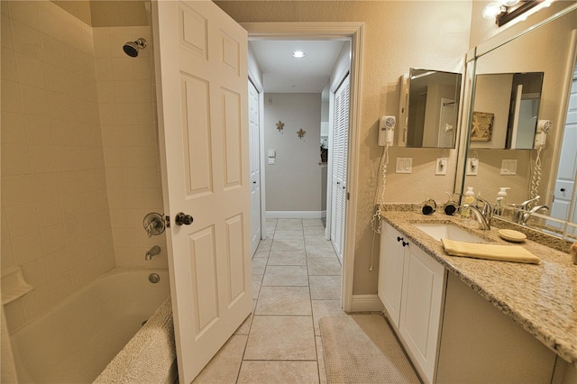 bathroom with tiled shower / bath combo, vanity, and tile patterned flooring