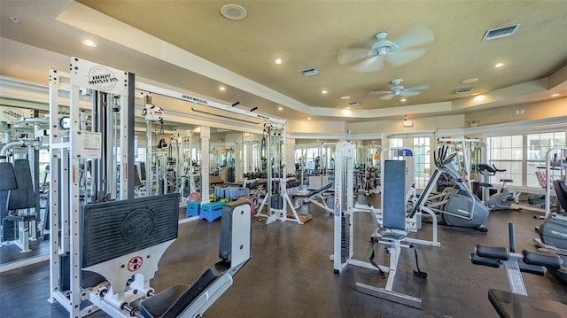 gym with ceiling fan and a tray ceiling