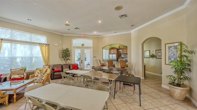 tiled dining area with plenty of natural light, crown molding, and french doors